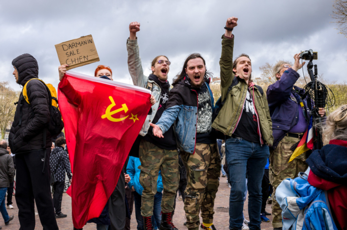 Photojournalisme - Des manifestant hurlent le bras en l'air à cote d un drapeau du parti communiste